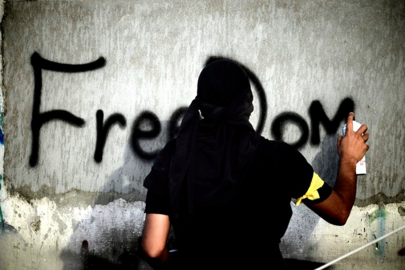 A Bahraini Shiite Muslim sprays the word