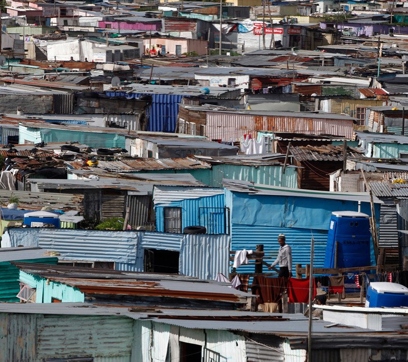 Residents walk through shacks in Cape Town's crime-ridden Khayelitsha township in this picture taken July 9, 2012. At least 11 people have died at the hands of vigilantes in the township since January as angry residents, tired of poor policing, take the law into their own hands. Picture taken July 9, 2012. To match Feature SAFRICA-CRIME/ REUTERS/Mike Hutchings (SOUTH AFRICA - Tags: CRIME LAW) - RTR34VDA